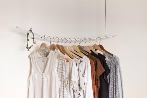 An artful display of blouses, sweaters, and other tops on hangers.