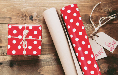 Red wrapping paper with white polka dots and a wrapped gift.
