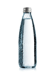 A glass water bottle with condensation drops on the outside sits in front of a white surface