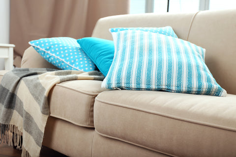 Image of beige couch with teal throw pillows and a striped throw blanket