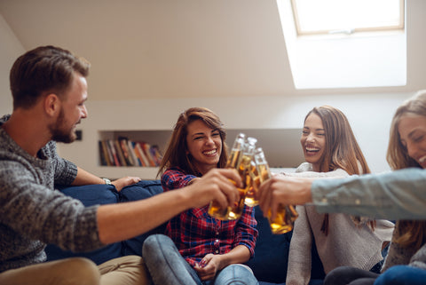 Group of friends clinking with beer and having a good time in the apartment