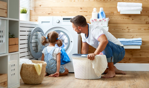 Happy father and daughter doing laundry with washing machine