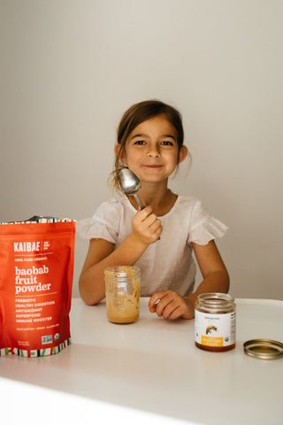 healthy girl eats kaibae organic baobab fruit powder mixed with honey to boost her immune system