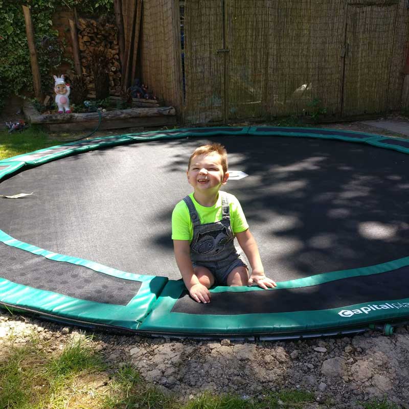 little boy on in-ground trampoline