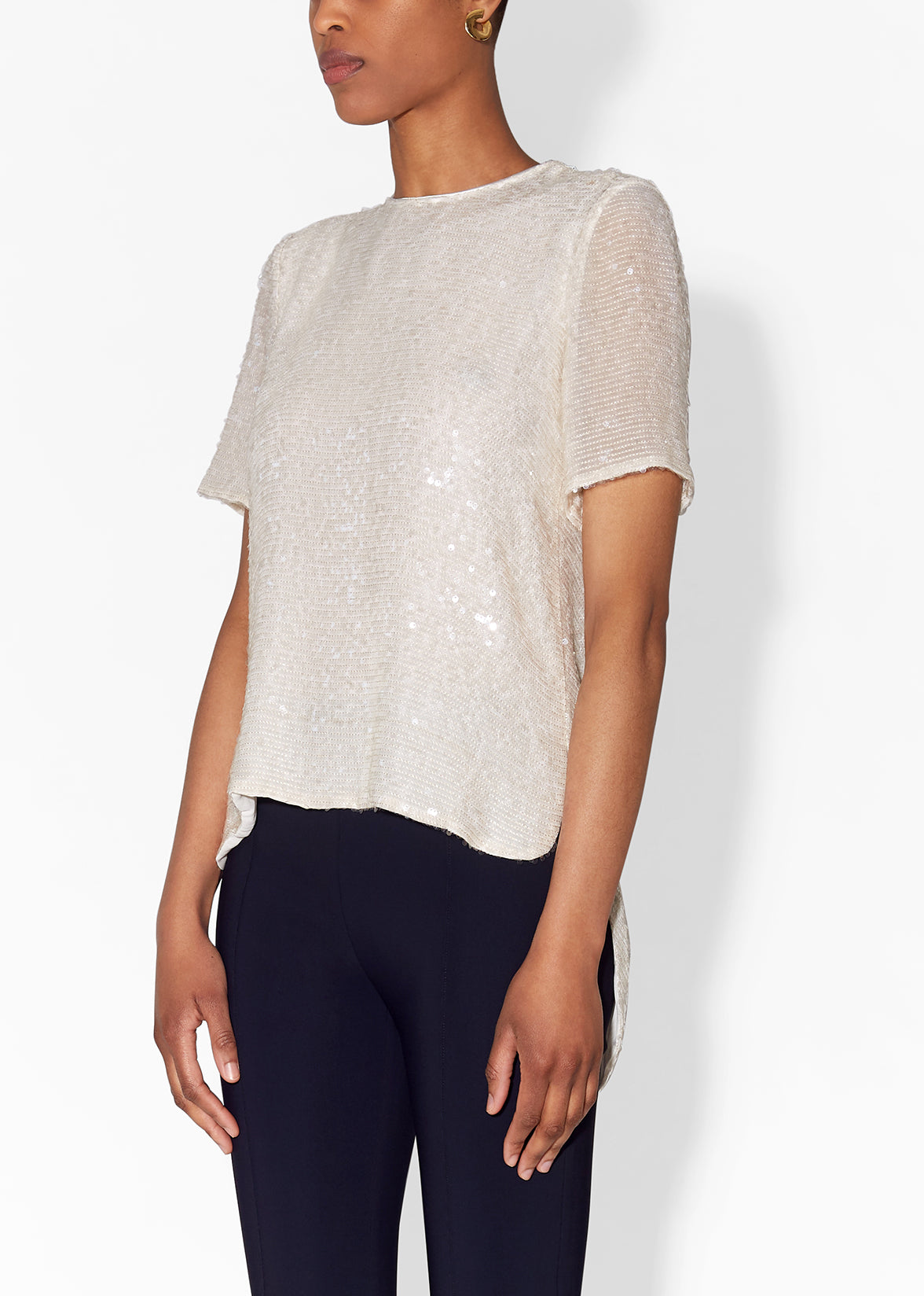 A side view of a sequin top on a model with black trousers