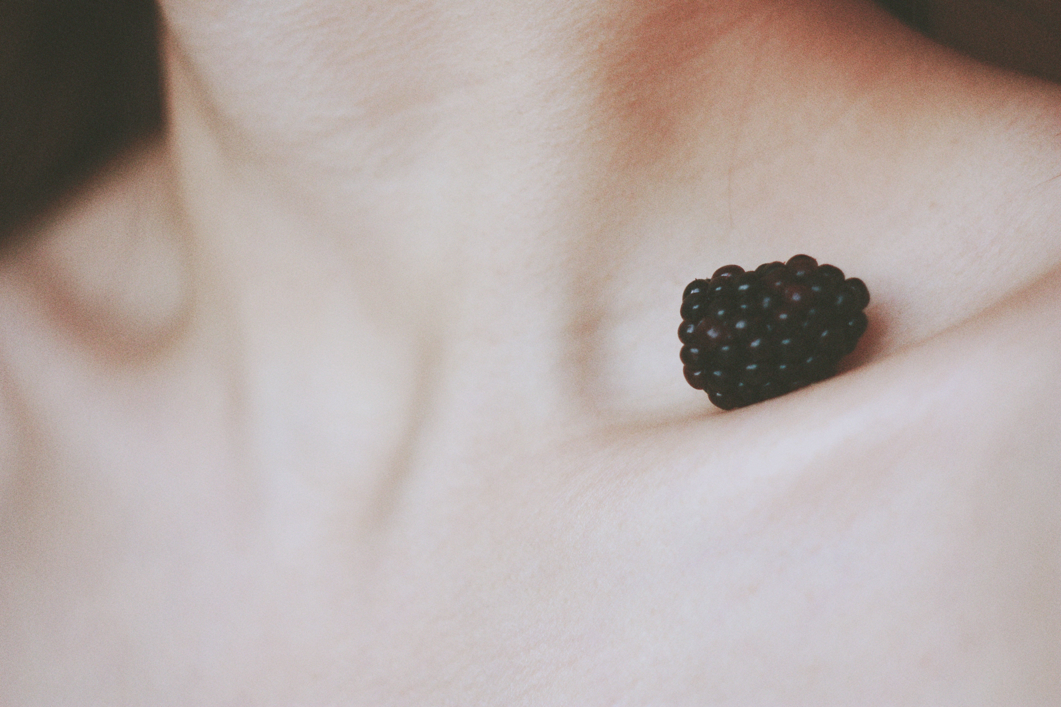 Closeup of a woman's chest with a blackberry in her neck. 
