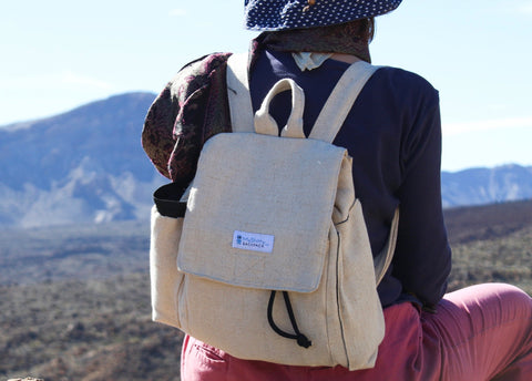 The beige hemp backpack is worn by a woman in a desert. It looks comfortable to wear.