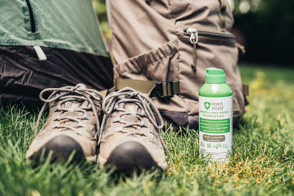 Hiking shoes and gear shown with a bottle of Insect Shield insect repellent permethrin spray