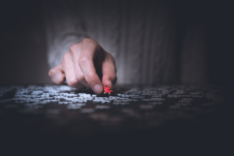 Person placing a piece of jigsaw puzzle down