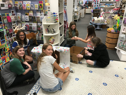 girl scout troop wrapping boxes to collect pet donations in periwinkle