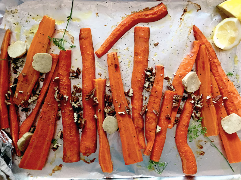 Roasted carrots with spiced butter on a baking sheet by Claire Tansey