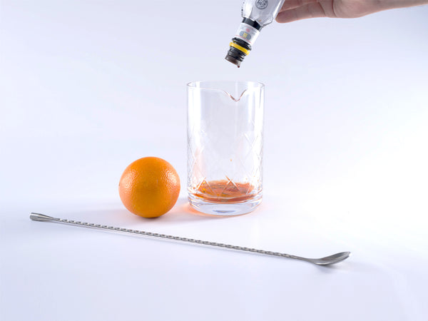 Bottle of bitters being dashed into mixing glass