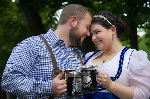 groom wearing a blue checkered shirt and lederhosen snuggling his bride in a white and blue bridal dirndl dress