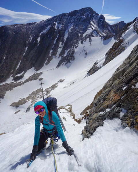 Emma Ely, Eiten's partner, climbs snow, ascending the Notch Couloir under blue skies.