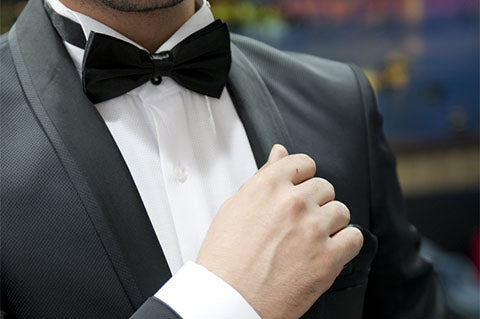 Man in black suit adjusting cuff links