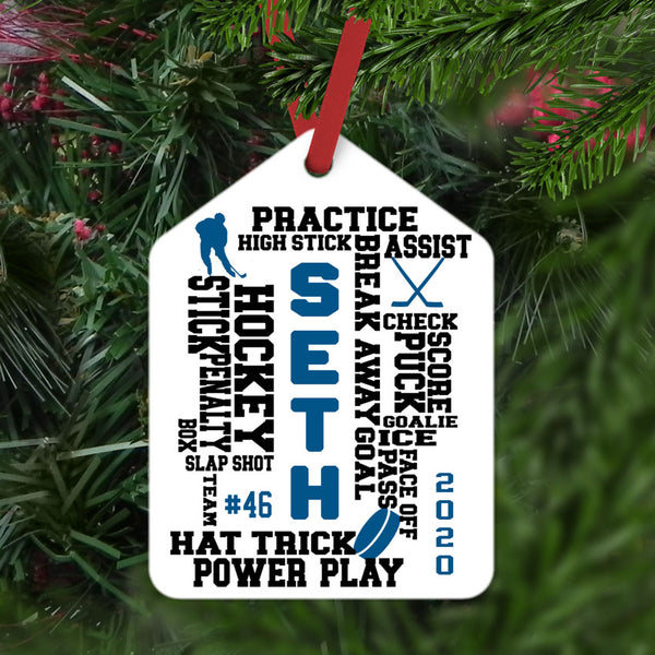 Randomly placed words about hockey on a gift tag shaped christmas ornament personalized with name jersey number and year.