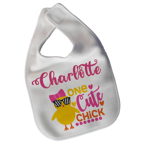 White baby bib with velcro closure with yellow chick a dee  wearing a bow and sunglasses boasting the text "One Cute Chick and any personalized name.