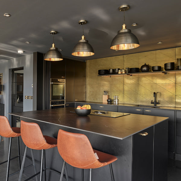 Kitchen in a barn conversion with brass splashback and pewter and brass pendants