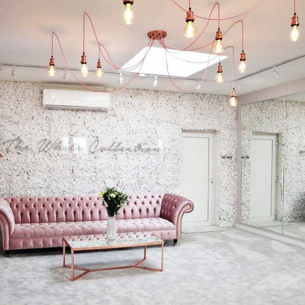 Pink velvet sofa and pink hanging lights in a bridal shop interior