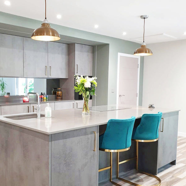 Concrete look kitchen interior with brass pendants above kitchen island