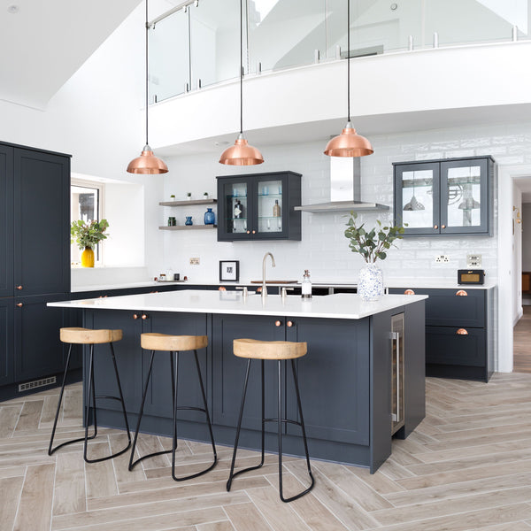 Open-plan kitchen interior with trio of copper pendants over kitchen island