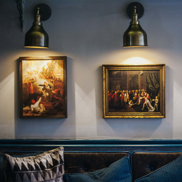 Navy restaurant interior with unique artwork lit up by handcrafted pewter wall lights