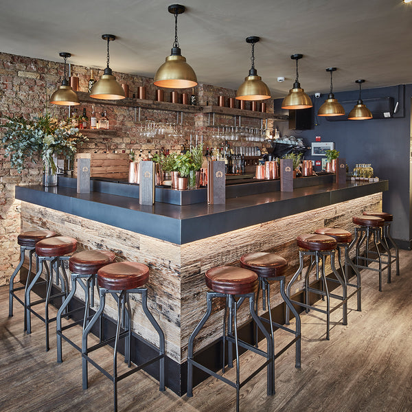 Bar interior with brass pendant lighting and handcrafted stools