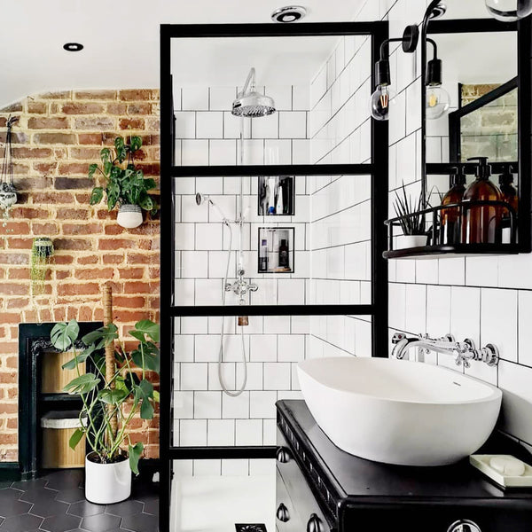 Industrial-style bathroom interior with exposed brick walls, tiles and vintage wall light