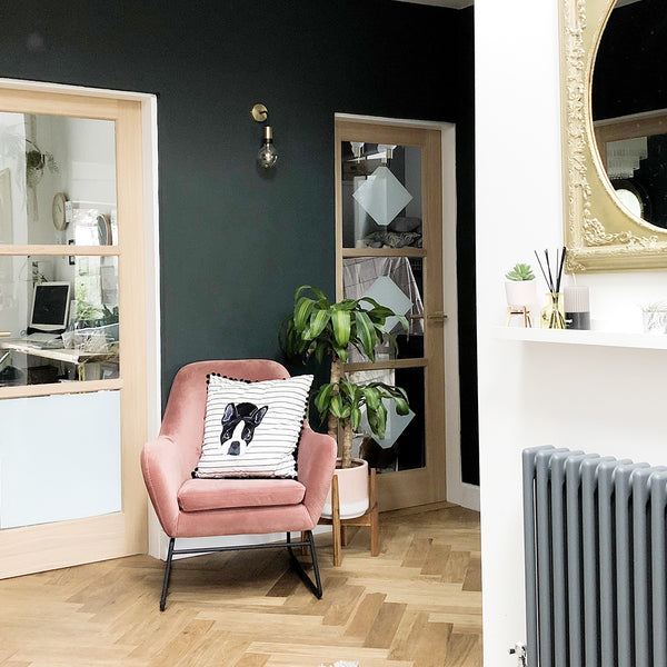Cosy corner in a home with dark walls, brass wall light and pink velvet chair