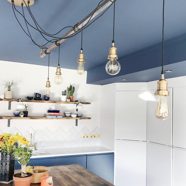 Modern kitchen interior design with blue walls and hanging industrial brass lights