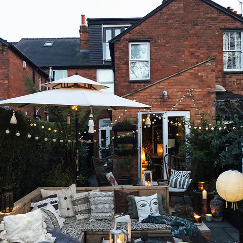 A stylish garden with fairly lights, canopy and outdoor sofa with cushions