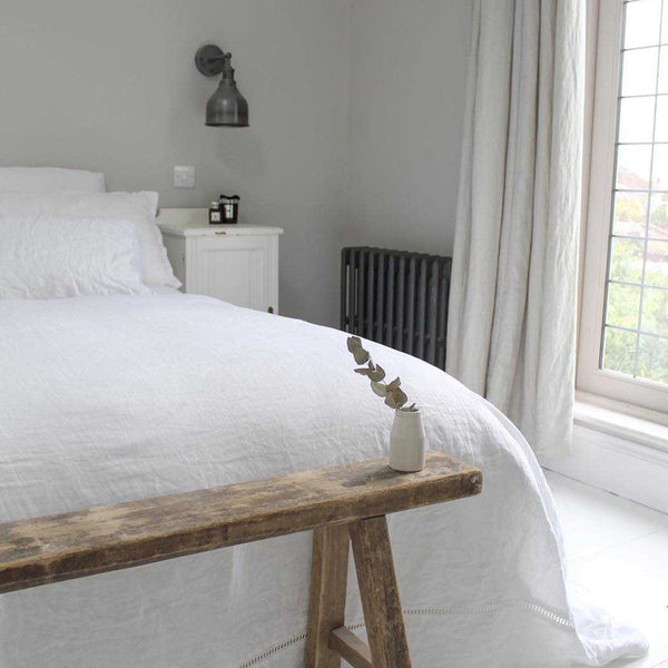 A white bedroom interior with driftwood furniture and metallic wall lights by Industville