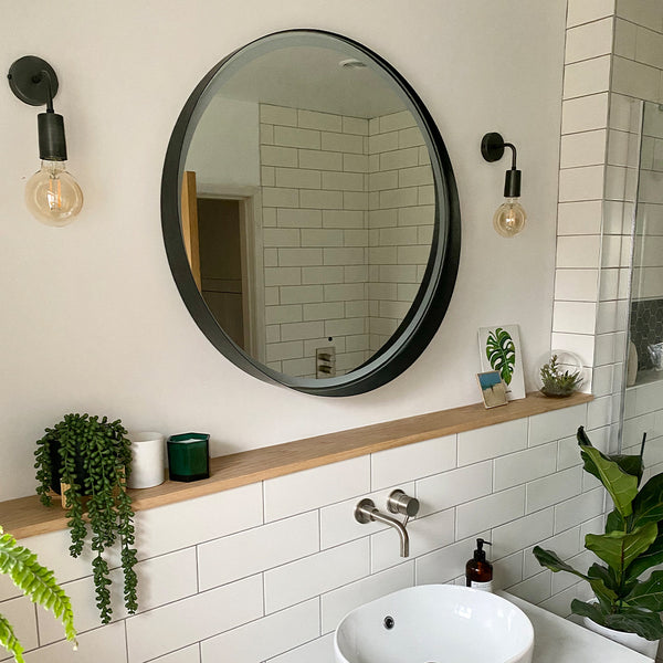 Bathroom with circular mirror above wooden shelf
