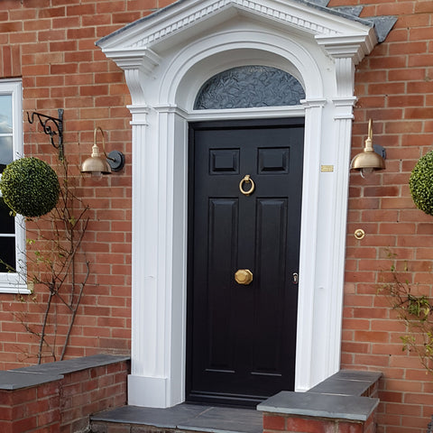 A grand black front house door with brass highlights and lights by Industville
