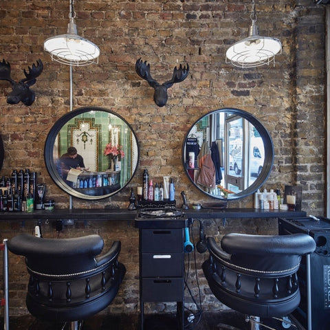 A hairdressing salon with exposed brick wall and retro cage pendant lights