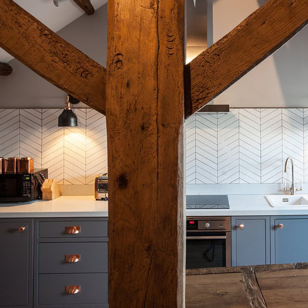 wooden beams in a rustic kitchen interior with white tiles and industrial wall lights