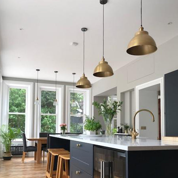 Modern kitchen diner interior with a trio of brass industrial pendant lights 