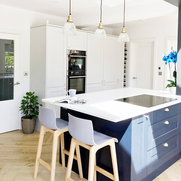 white and blue coloured residential kitchen with hanging light fixtures in line with interior lighting trends