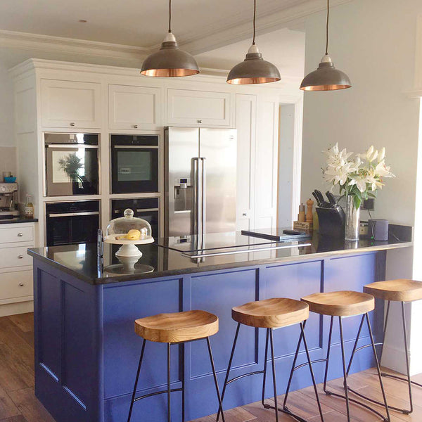 A kitchen interior with a trio of industrial pendants above the kitchen island