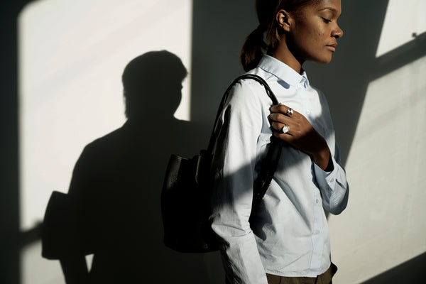 Female model standing in the sunlight wearing a leather backpack