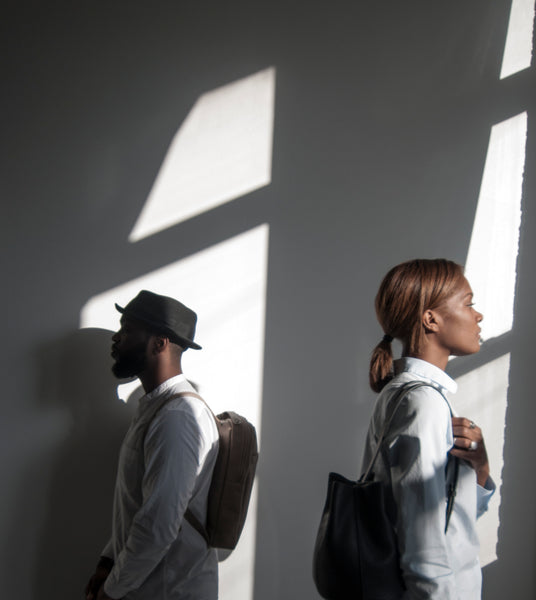 Male and female models standing in the sunlight wearing leather backpacks