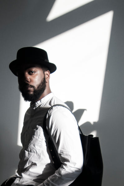 Male model standing in the sunlight wearing a leather backpack