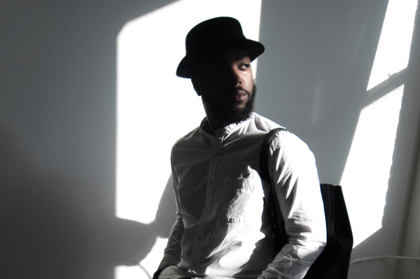 Male model standing in the sunlight wearing a leather backpack