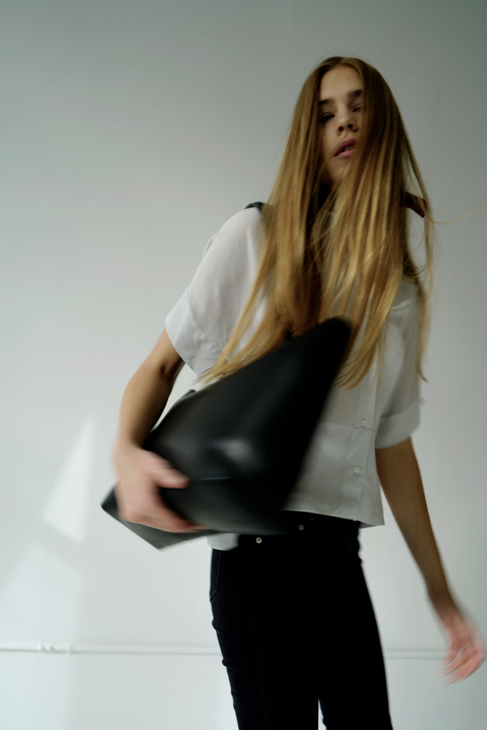 Female model in motion with large black leather tote