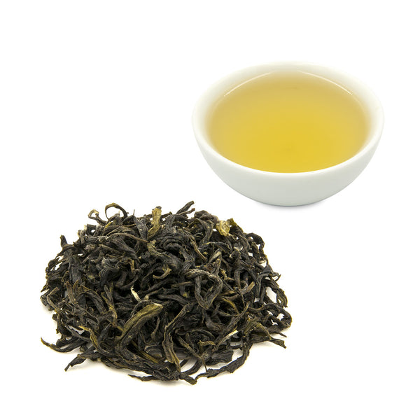 Brewed Bi Luo Chun Green Tea in white tea cup behind a pile of dry tea leaves