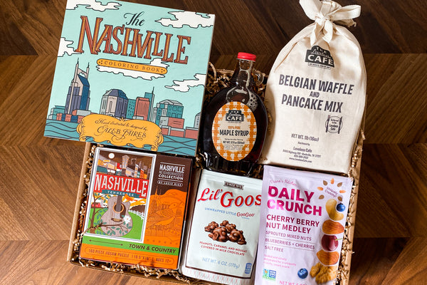 At Home Survival Kit gift Box from Batch + Nashville Scene.  Limited edition gift box includes the Spirit of Nashville 160-piece puzzle, Lil’ Goos, Daily Crunch Cherry Berry Nut Medley, The Nashville Coloring Book, Loveless Cafe Pancake Mix, Loveless Cafe Maple Syrup.