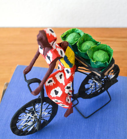Detail image of Zambian woman, wearing baby, bicycling with cabbages. Folk art made in Zambia.