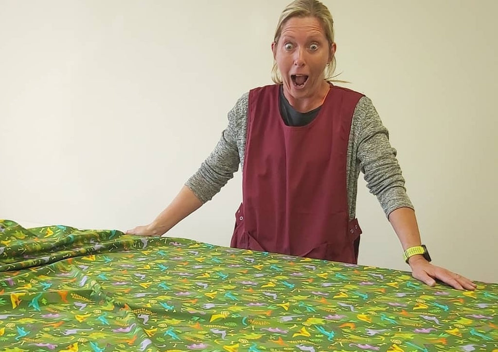 MAndy looking shocked at an unrolled swatch of Dinos fabric covering the pattern cutting table.
