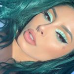 Face of young woman with bright aqua eyeshadow and turquoise hair
