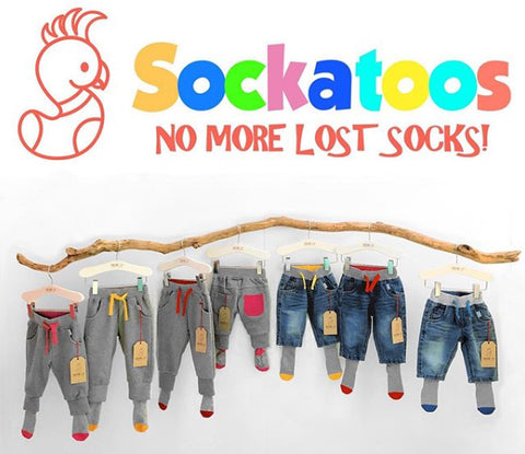 photo of multiple pairs of baby and toddlers sized trousers hanging on a branch all with sewn in socks, sockatoos logo above
